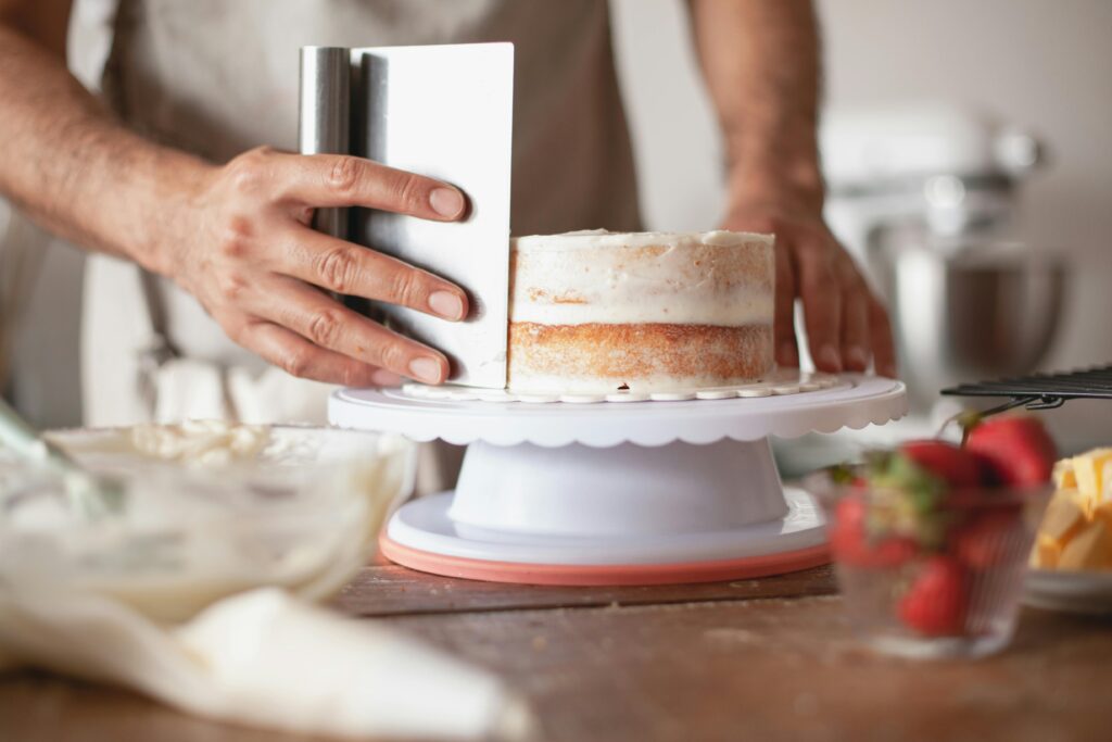 Pâtissier en train de lisser un gâteau sur un plateau tournant